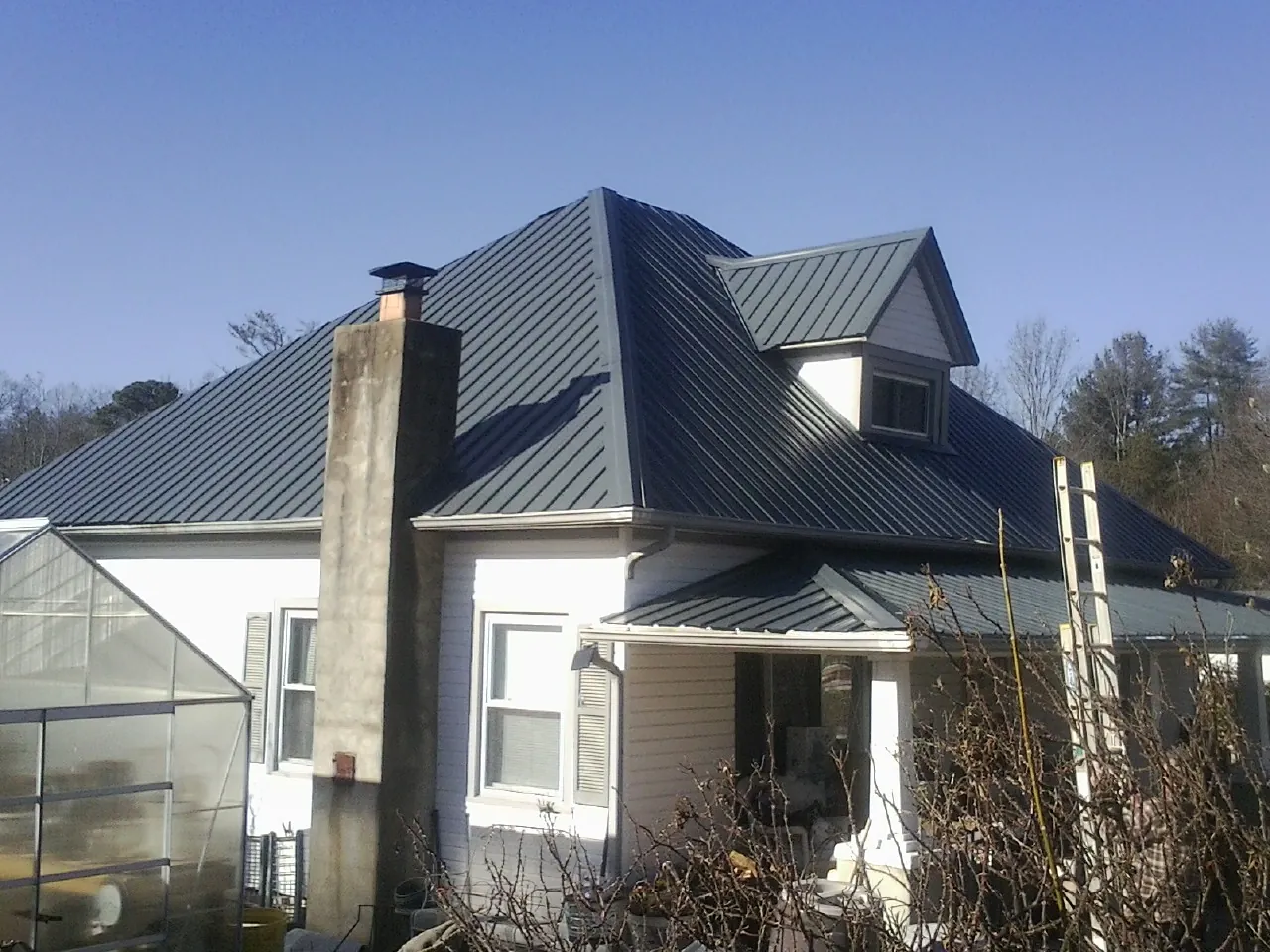Dark blue standing seam metal roof on a white farmhouse with dormer — Slate & Tile Roof Repair by Roofing Brothers in Maple Shade