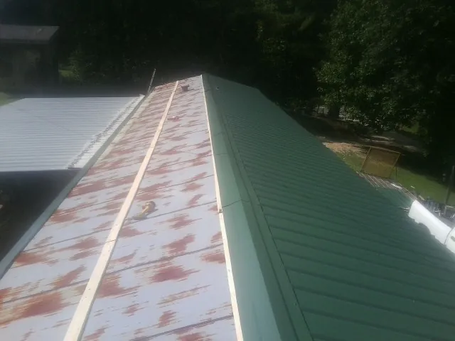 Old rusted panels beside newly installed green metal roofing — Wind Damage Roof Repair by Roofing Brothers in Maple Shade