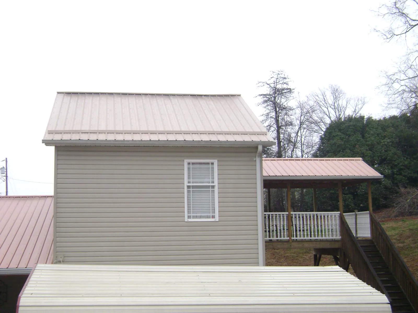 Tan metal roofs on a two story addition and attached porch, from a Roof Replacement job in Maple Shade