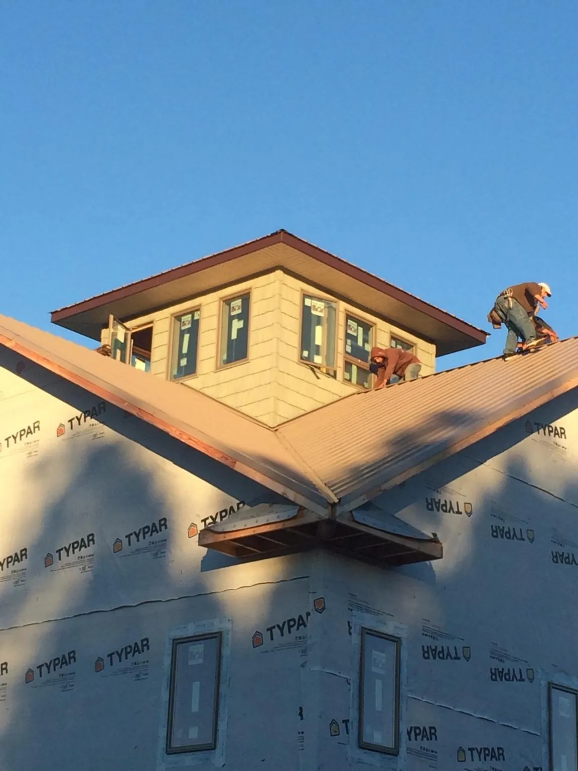 Roofers working around a rooftop cupola on a new metal roof at sunset — Roof Waterproofing in Maple Shade by Roofing Brothers